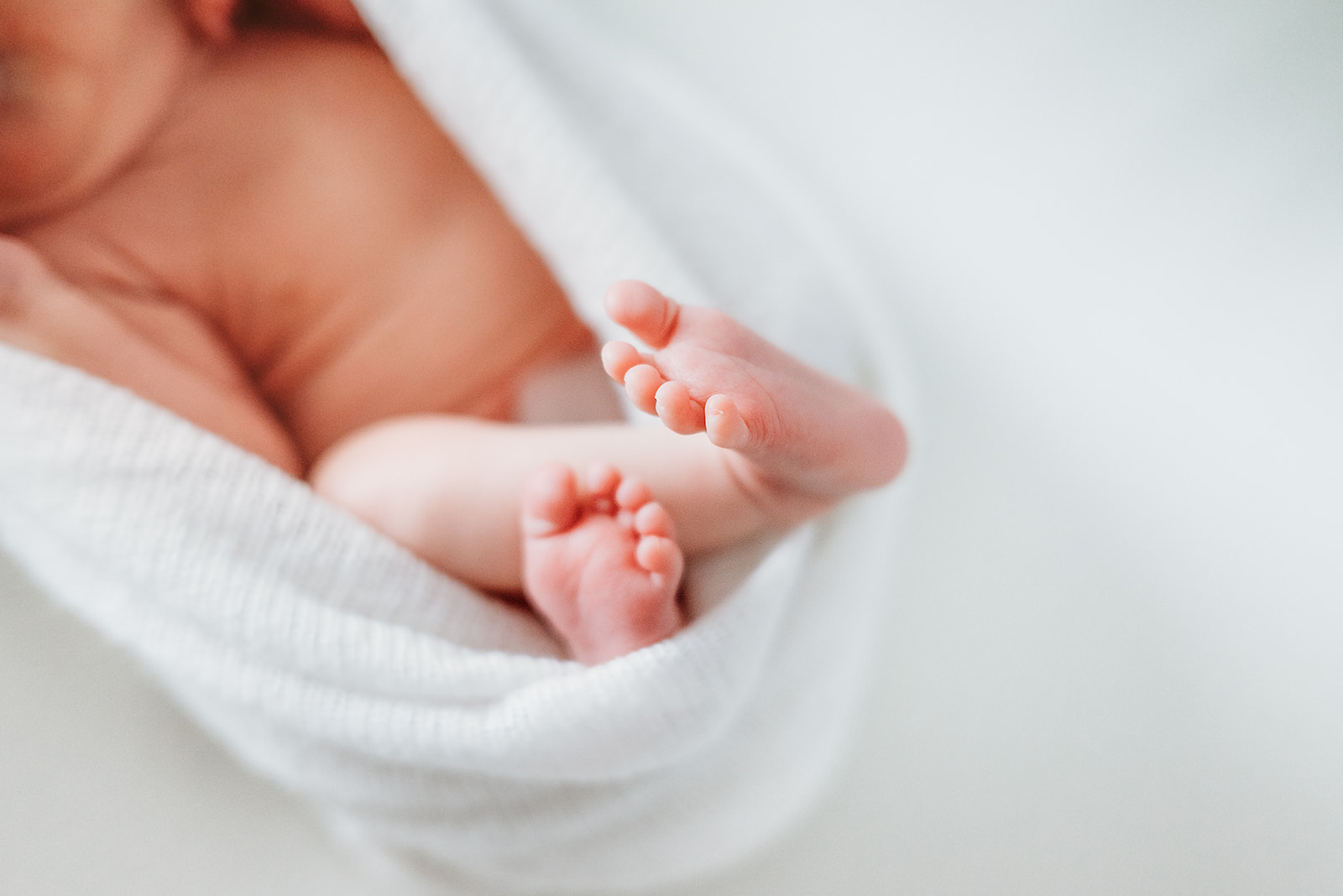 Detail shot of newborn feet while wrapped in a white blanket during newborn session with Scarlet Oak Photography in Cumming, GA