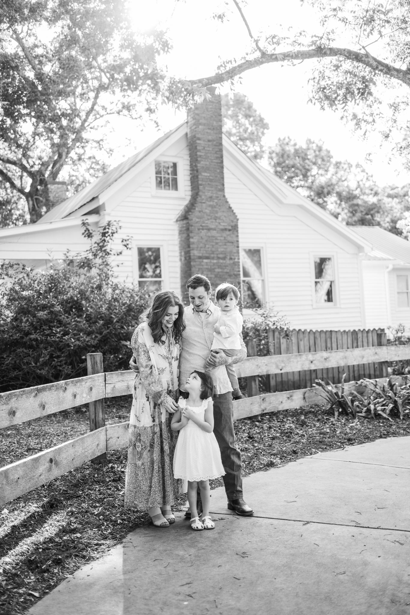 Mom, Dad, Son and Daughter pose for photo session in front of farm house in black and white image.