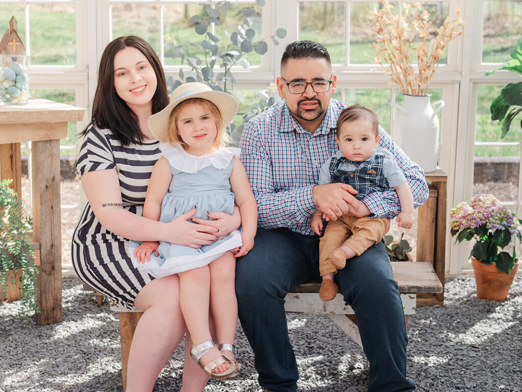 Mom, Dad, Son and Daughter sit on bench together and smile at camera in Spring Mini Session in Dawsonville.