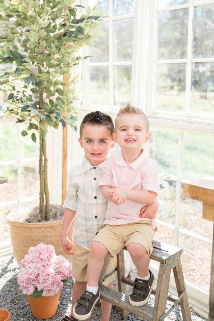 Toddler brothers smile while playing in a greenhouse before visiting alpharetta playgrounds