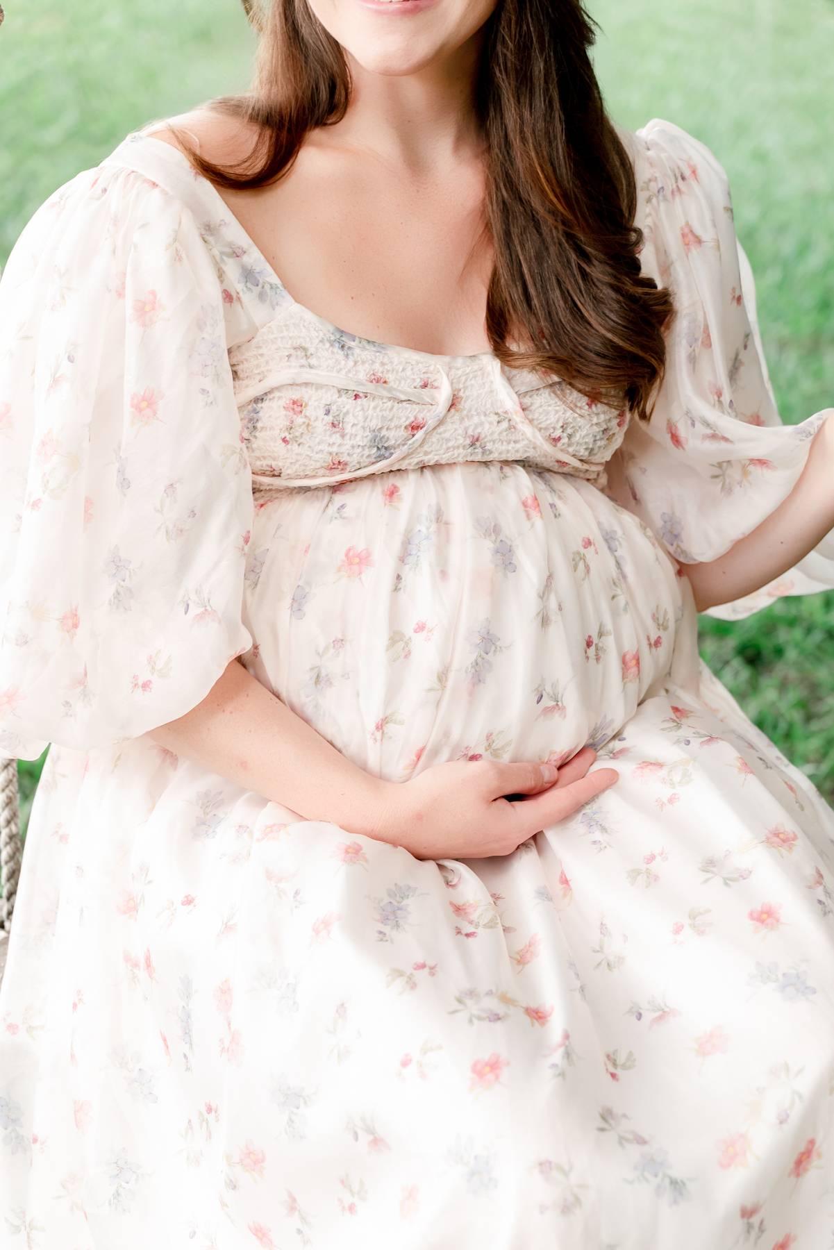 Mom places hand on pregnant belly in flower field for North Atlanta Maternity session.