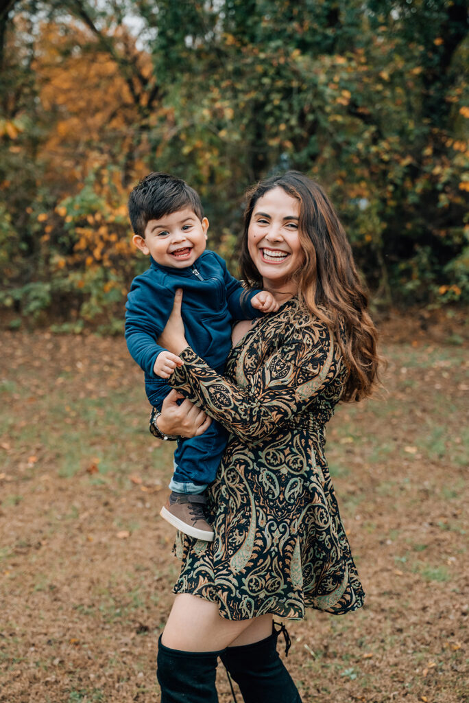 Mother holding toddler son in colorful leaves during Cumming GA fall family portraits