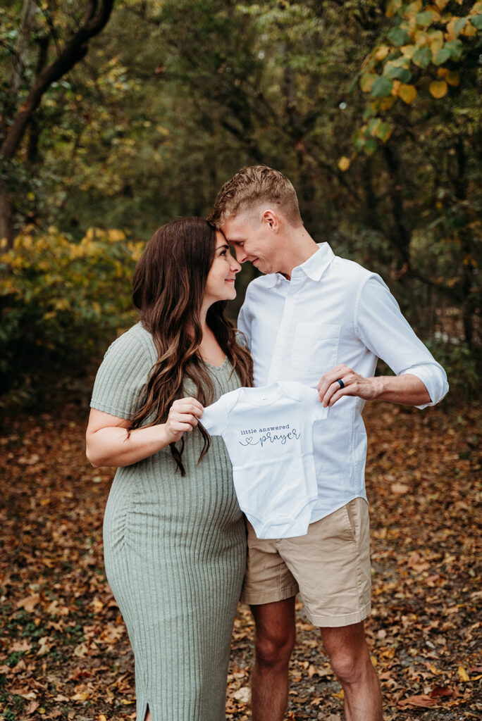 Couple sharing a kiss during Cumming GA fall family portraits in a wooded park.
