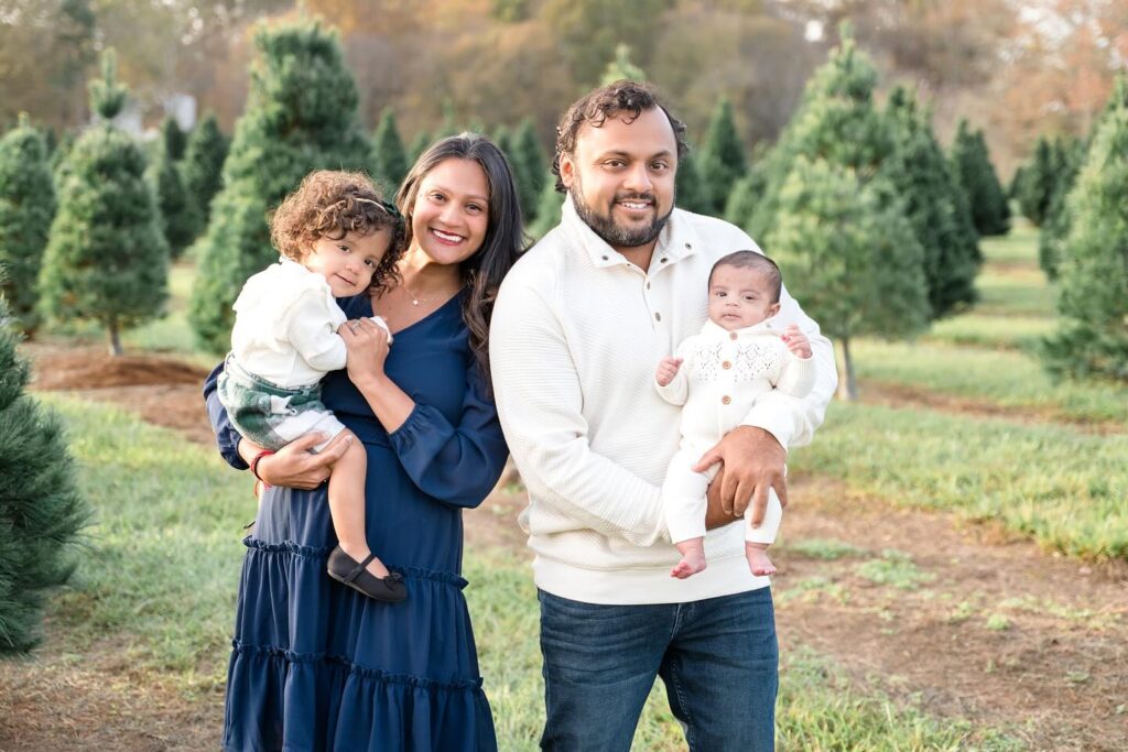 Mom holding daughterand dad holds son while showing off their blue and white christmas outfits for family photos.