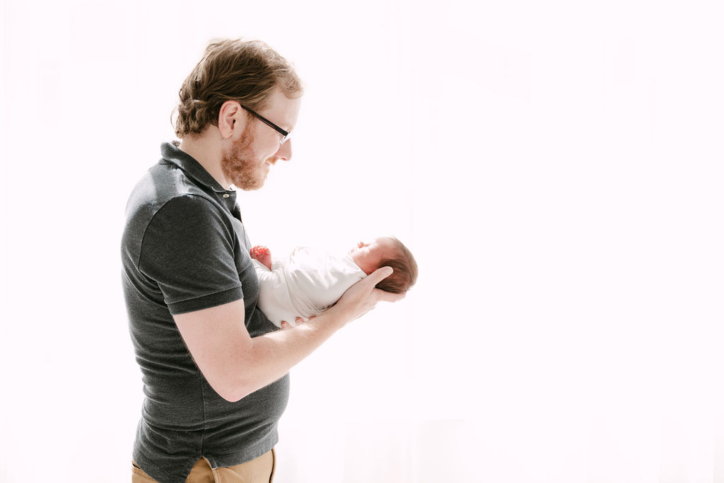Dad admires newborn baby in Alpharetta newborn session.