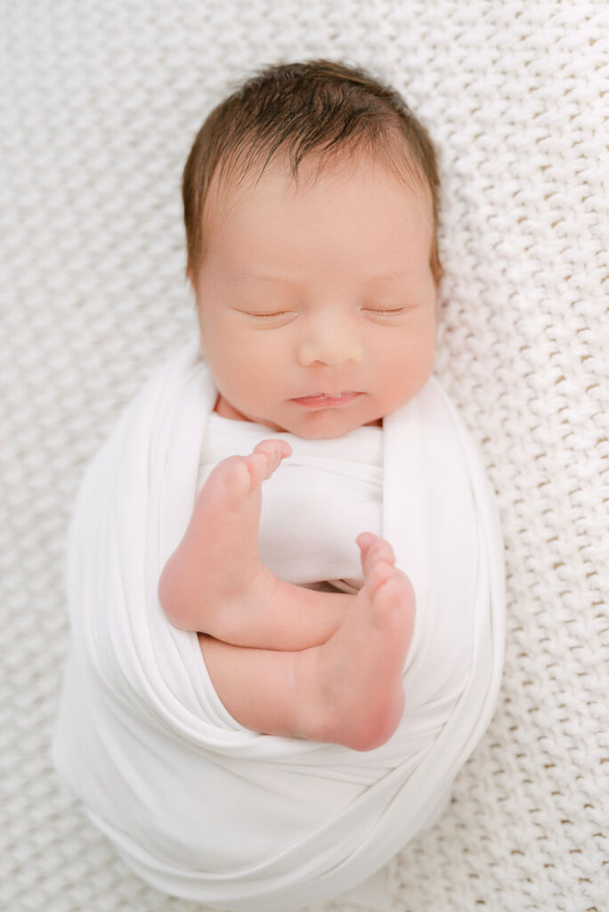 Baby wrapped tightly in white blanket in newborn photography session in Alpharetta. 