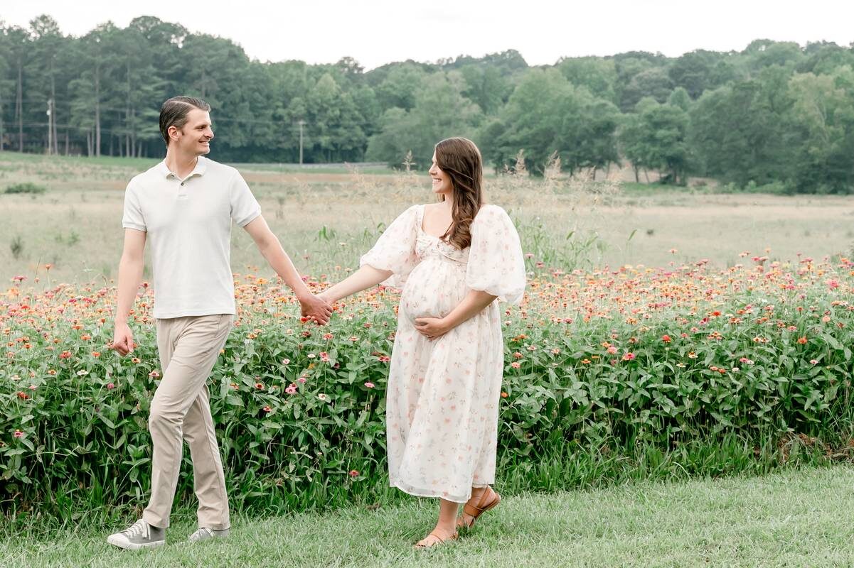 Husband and wife walk hand in hand in a flower field at Prospect Farms.