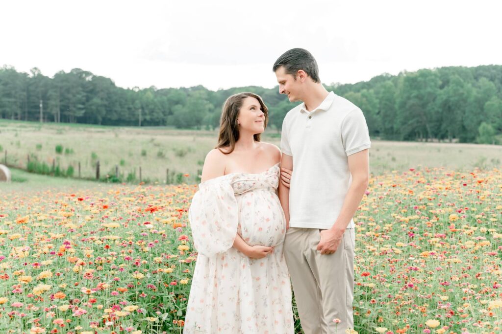 Husband and wife look lovingly at each other in a flower field at Prospect Farms.