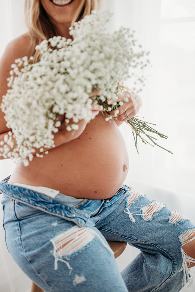 Mom shows of belly using flowers as a top in Woodstock Maternity Session.